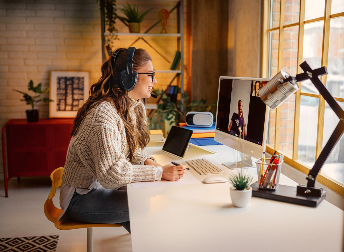 Woman sitting at desk with headphones on a video call at her desktop computer