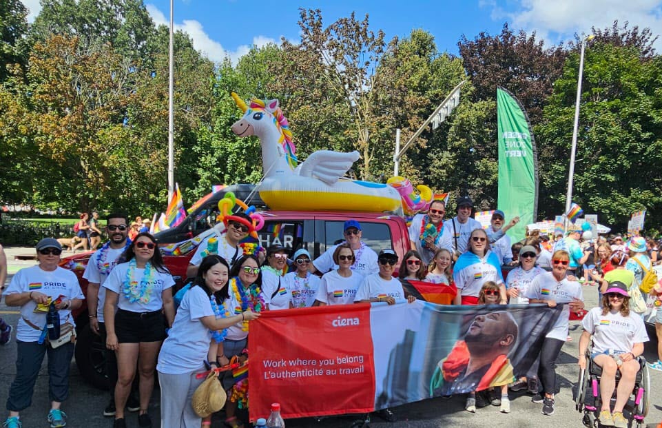 people at a parade holding a banner in front of a car with a unicorn float on top of it