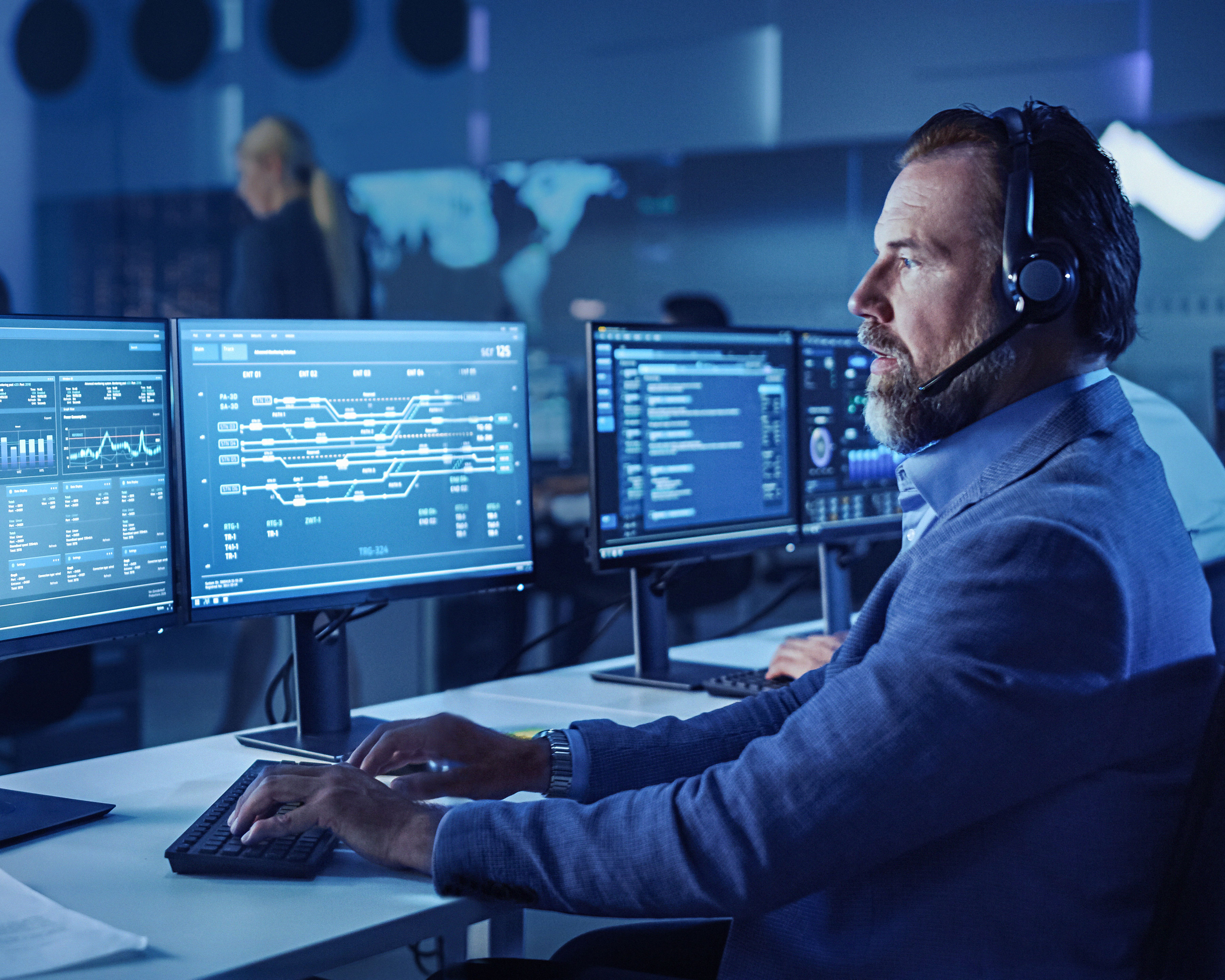 Man with headset in front of row of computers