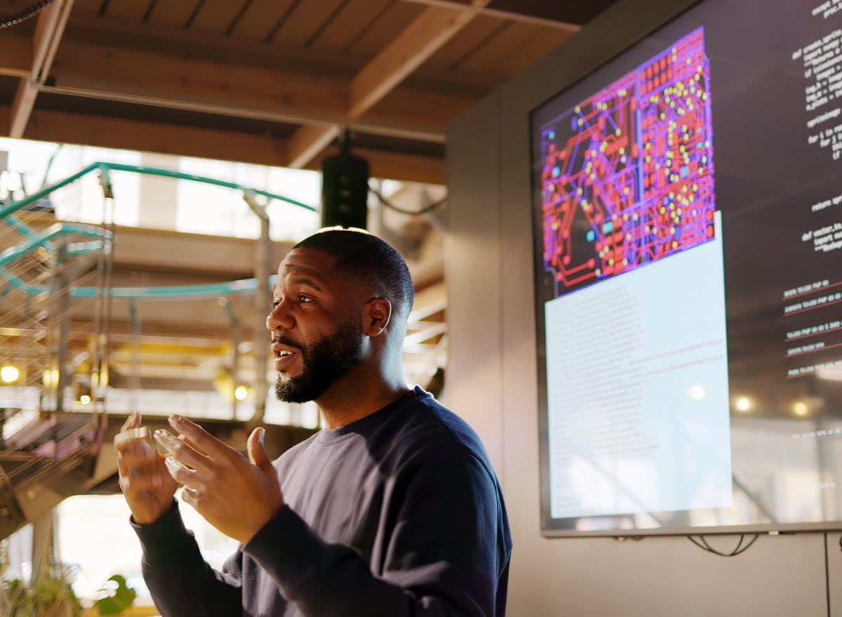 Man speaking in front of computer screens