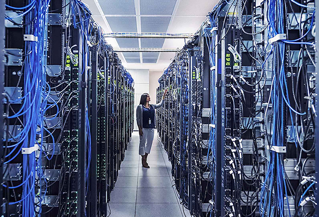 a woman walking through a room with data servers